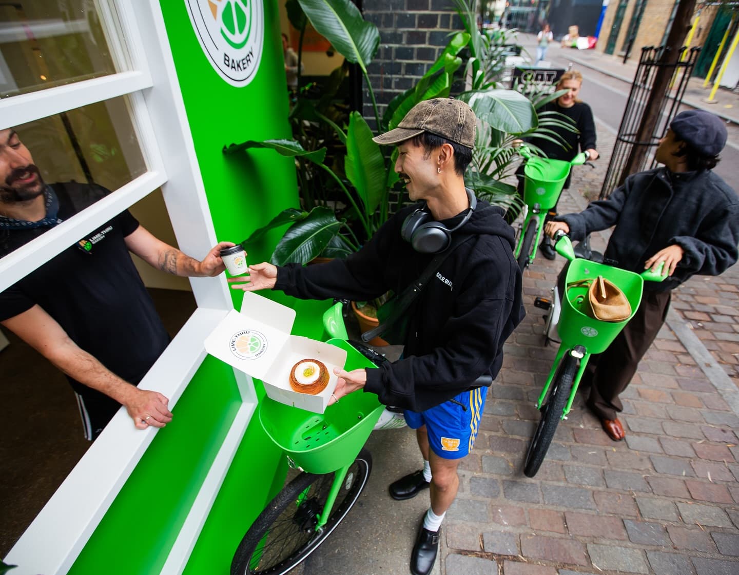 A rider collects a coffee and cronut box from the Lime-Thru Bakery bike-through window